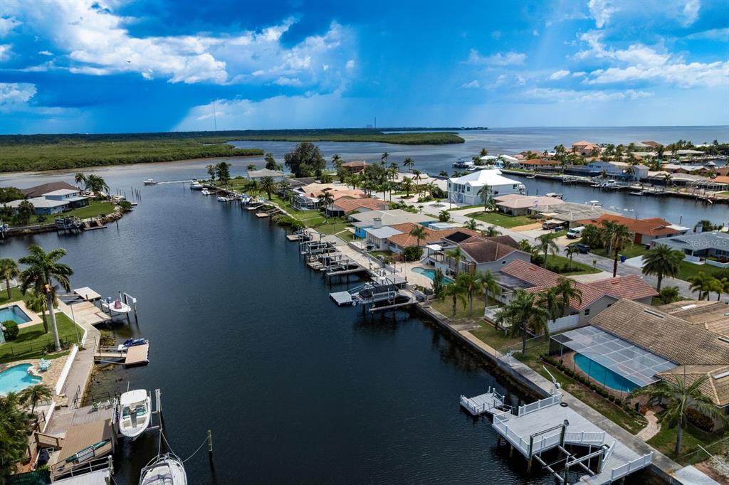 An aerial view shows waterfront homes with private docks along a canal leading to open water — 5008 GLENN DRIVE, NEW PORT RICHEY, FL