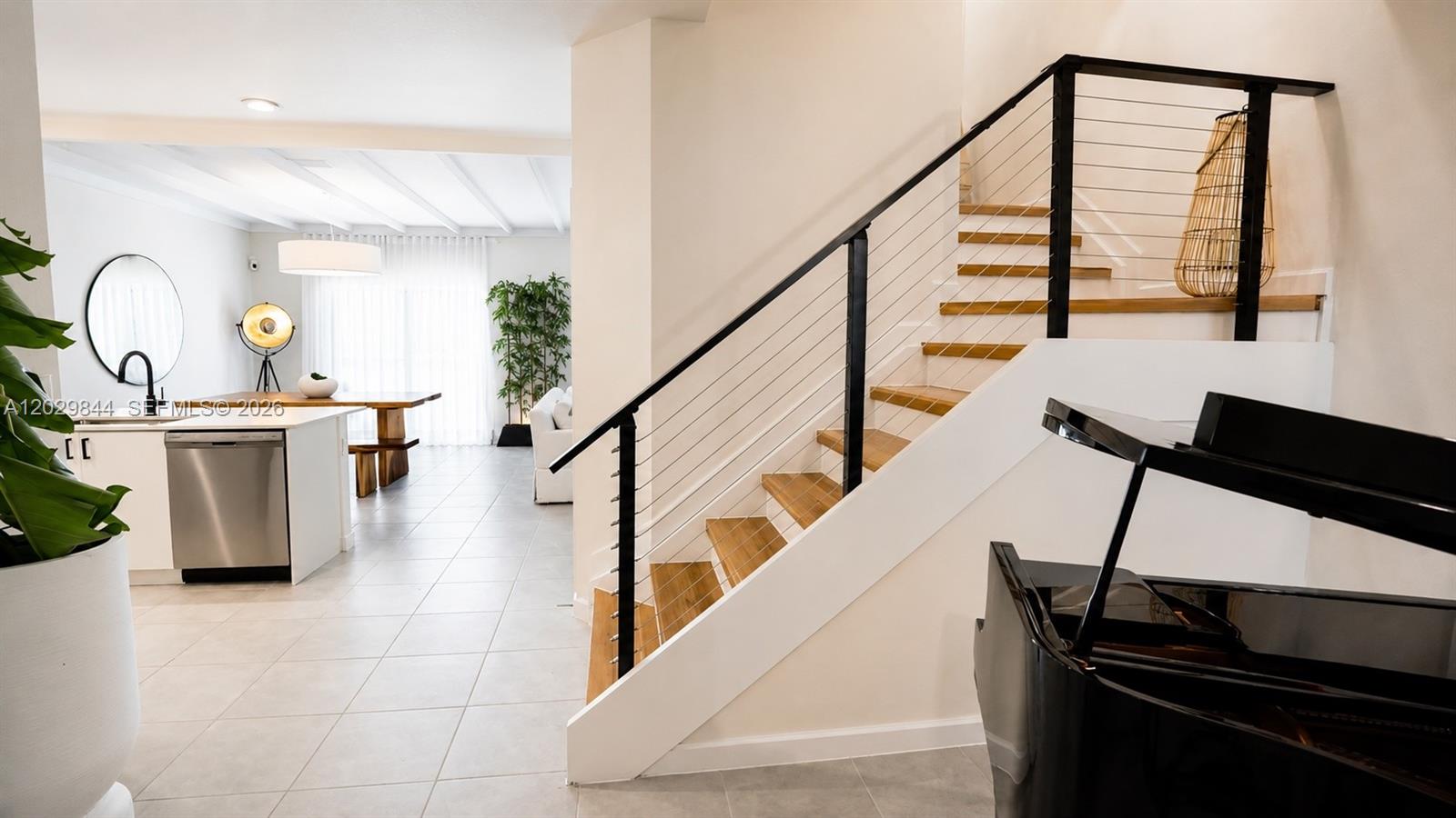 A staircase with a cable railing sits beside a grand piano in a modern home — 671 NW 204th St, Miami Gardens FL 33169, MIAMI GARDENS, FL