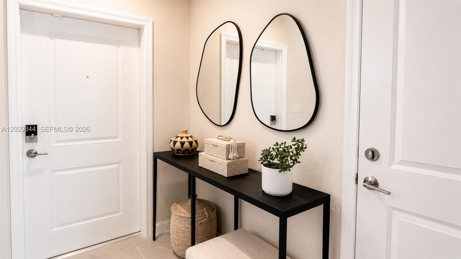 An entryway features a black console table, two oval mirrors, and a woven basket — 671 NW 204th St, Miami Gardens FL 33169, MIAMI GARDENS, FL