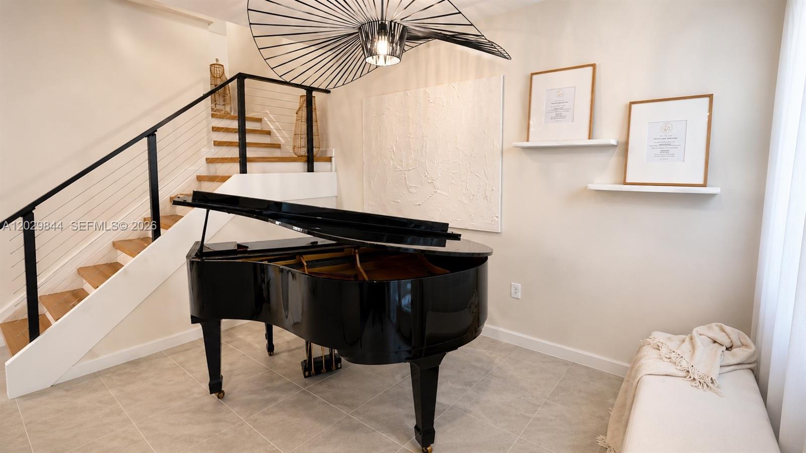 A black grand piano sits in a room with a staircase and modern light fixture — 671 NW 204th St, Miami Gardens FL 33169, MIAMI GARDENS, FL