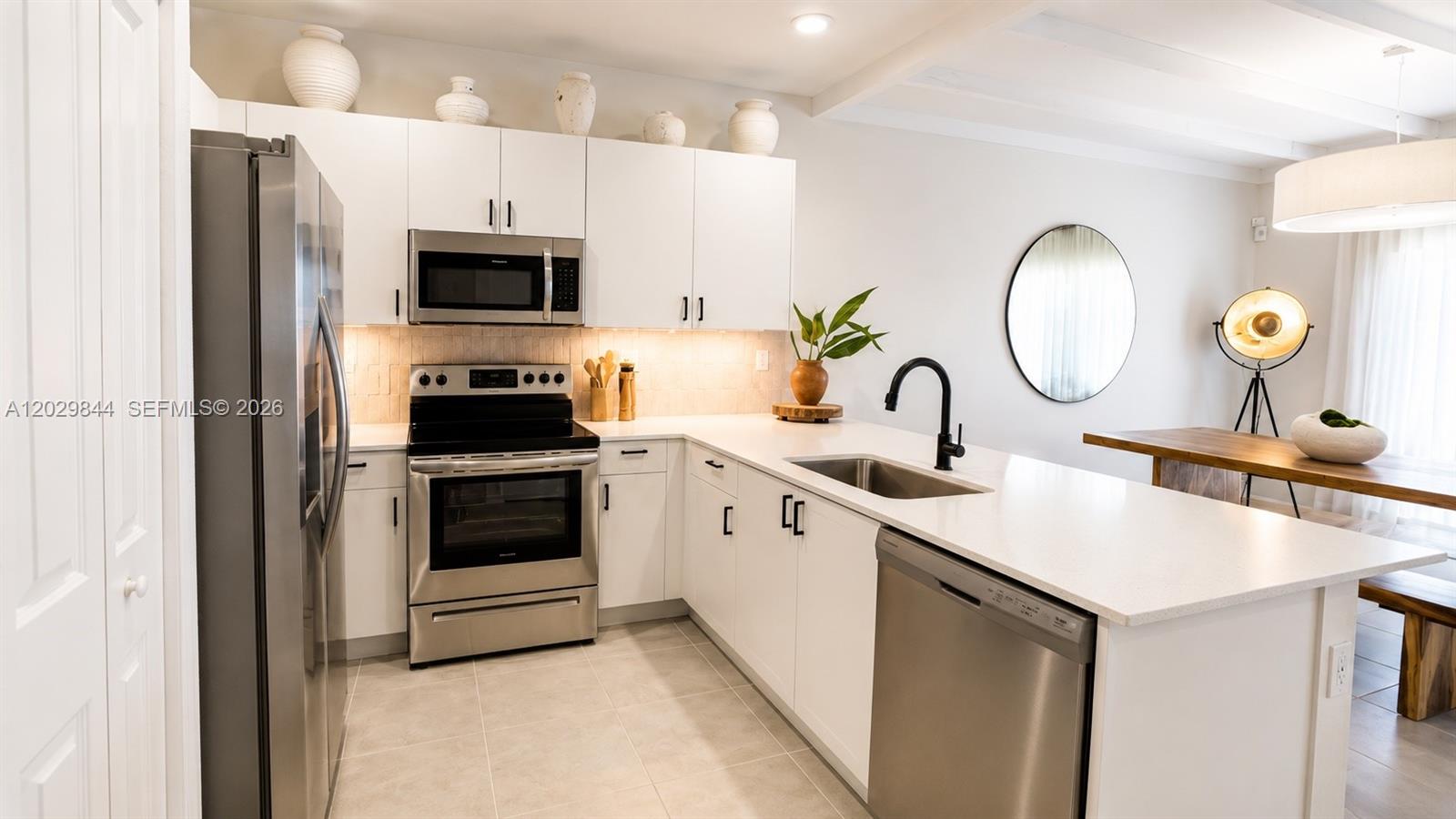A modern kitchen features white cabinets, stainless steel appliances, and a white quartz countertop island — 671 NW 204th St, Miami Gardens FL 33169, MIAMI GARDENS, FL
