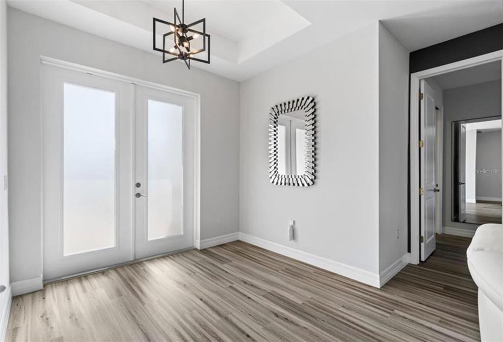A bright entryway features light wood-look flooring, a modern chandelier, and a decorative wall mirror — 1017 NW 15TH TERRACE, CAPE CORAL, FL