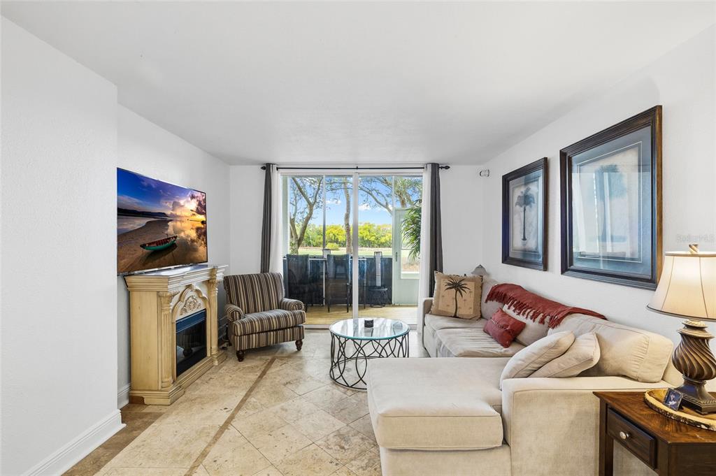 A living room features tile floors, a fireplace, a sectional sofa, and a sliding glass door — 2333 FEATHER SOUND DRIVE UNIT A101, CLEARWATER, FL