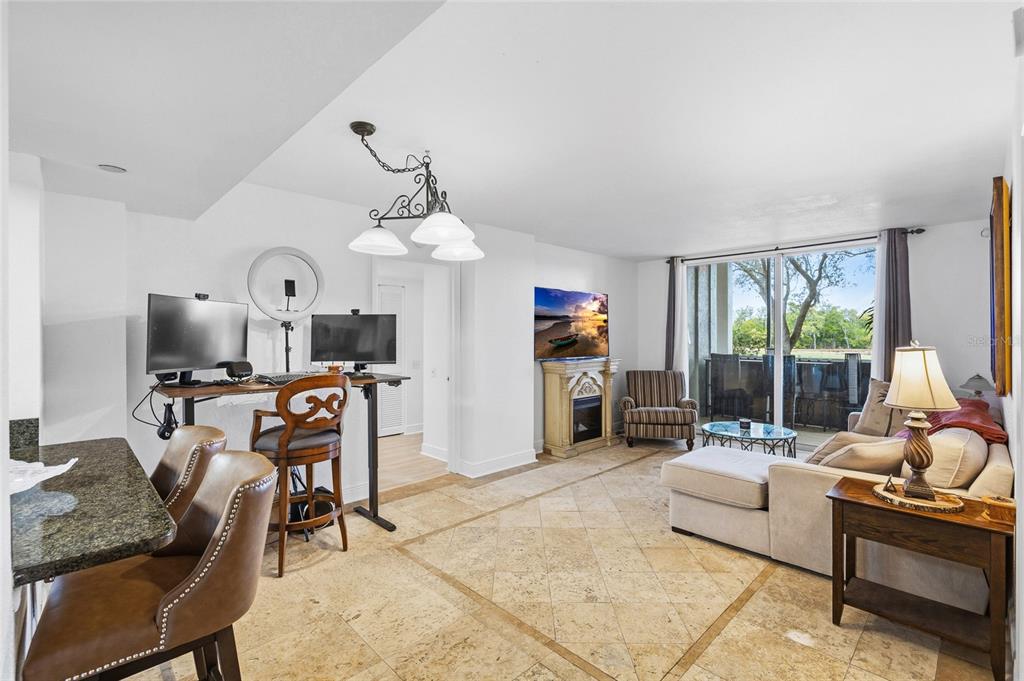 A living room with tile floors, a fireplace, a desk area, and a sliding glass door — 2333 FEATHER SOUND DRIVE UNIT A101, CLEARWATER, FL