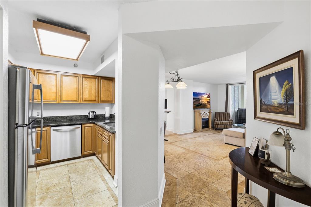 A kitchen with wood cabinets and stainless appliances opens into a living area with tile floors — 2333 FEATHER SOUND DRIVE UNIT A101, CLEARWATER, FL