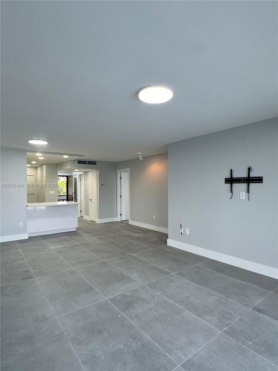 This living area features large gray floor tiles, light gray walls, and a kitchen pass-through — 1680 NE 191st St # 2, Miami FL 33179, MIAMI, FL