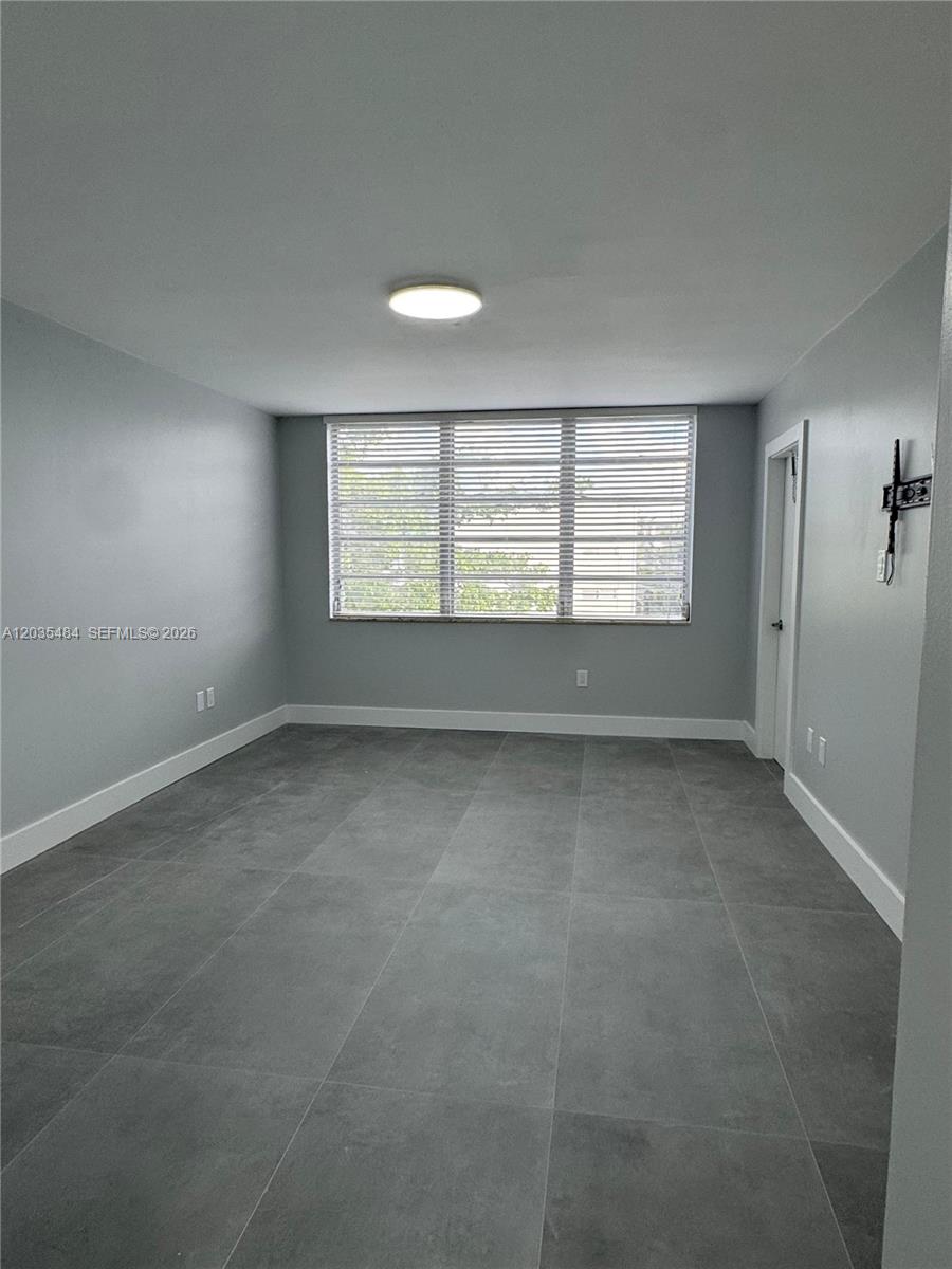 This room features gray walls, large gray floor tiles, and a window with blinds — 1680 NE 191st St # 2, Miami FL 33179, MIAMI, FL
