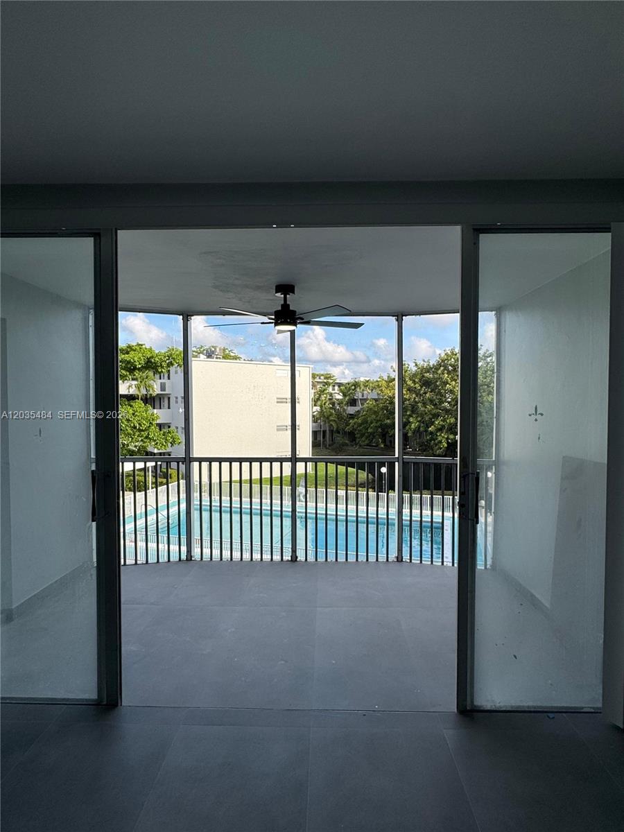 A view from inside a room looking out through sliding glass doors to a screened balcony — 1680 NE 191st St # 2, Miami FL 33179, MIAMI, FL