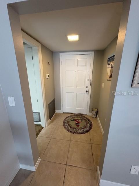 An entryway features a white door, tile flooring, a circular rug, and a recessed light — 147 BLUFF VIEW DRIVE UNIT 303, BELLEAIR BLUFFS, FL