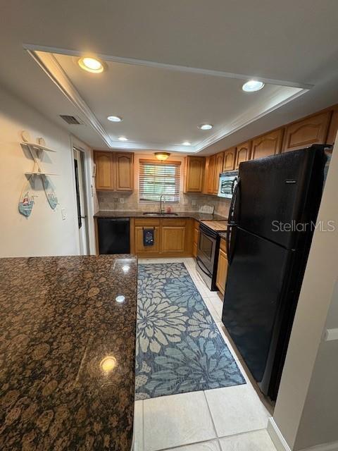 A kitchen features wood cabinets, granite countertops, a black refrigerator, and a floral area rug — 147 BLUFF VIEW DRIVE UNIT 303, BELLEAIR BLUFFS, FL