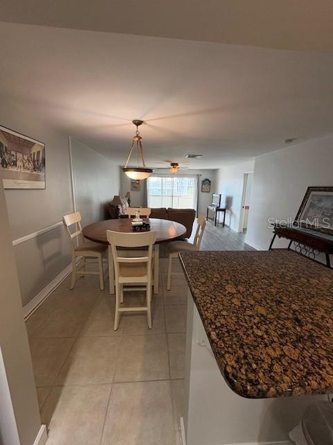 A dining area with a round table and chairs sits adjacent to a granite-topped kitchen island — 147 BLUFF VIEW DRIVE UNIT 303, BELLEAIR BLUFFS, FL
