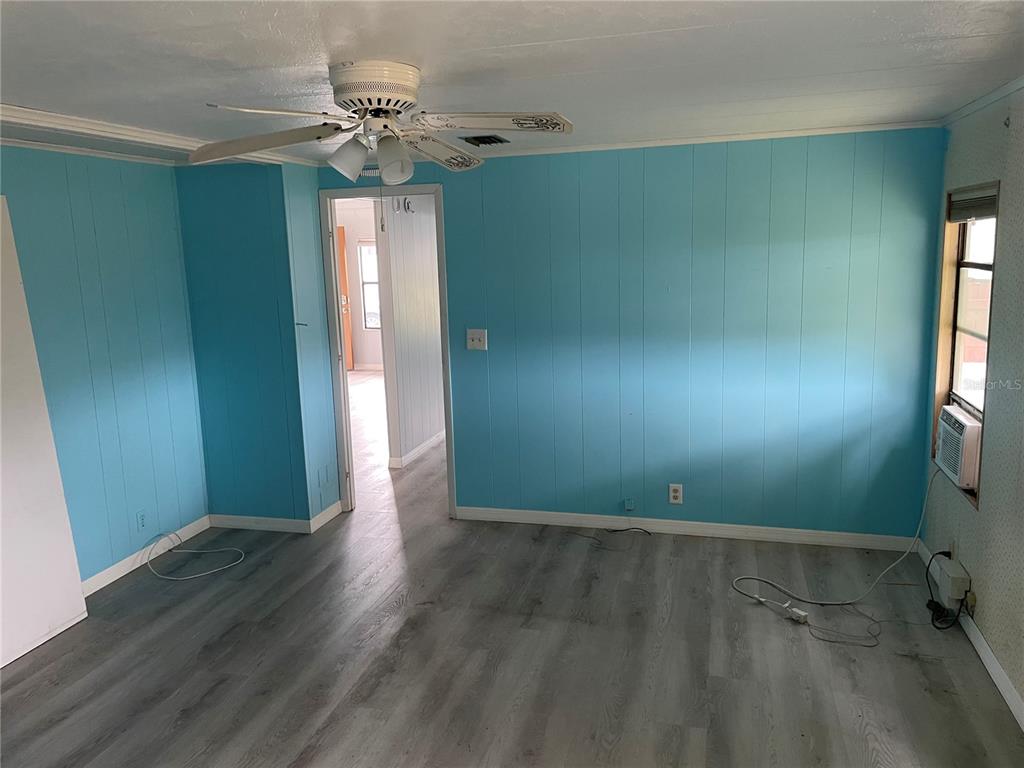 A room with light blue paneled walls, gray wood-look flooring, and a ceiling fan — 2102 CANOPY CIRCLE UNIT 150, ZELLWOOD, FL