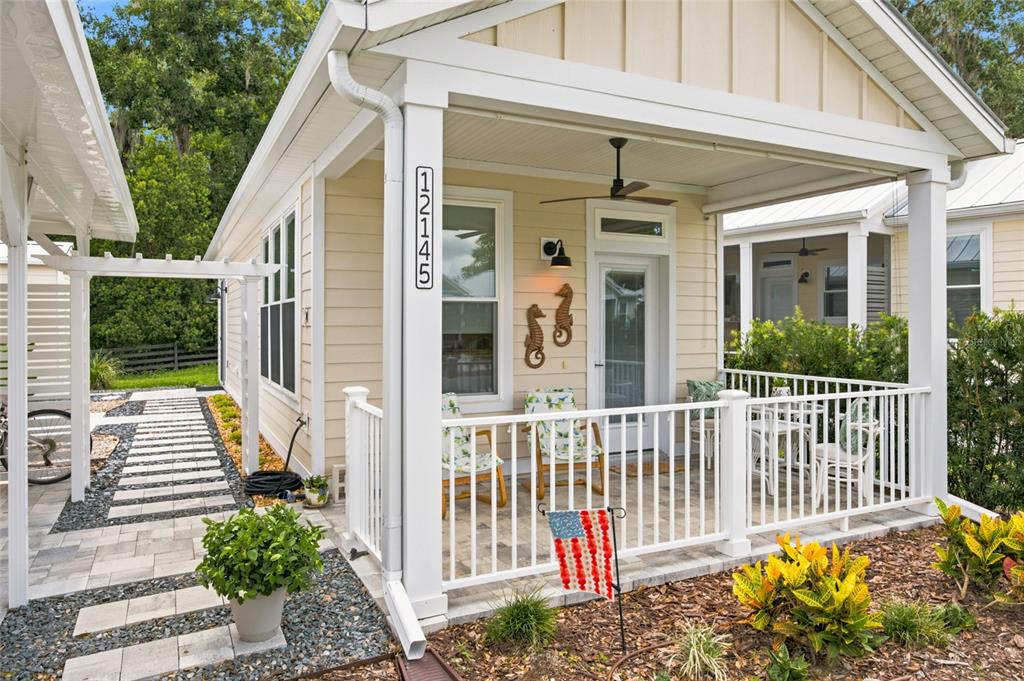 A light yellow cottage features a covered front porch with white railings and a walkway — 12145 GRAND OAK LANE, OXFORD, FL