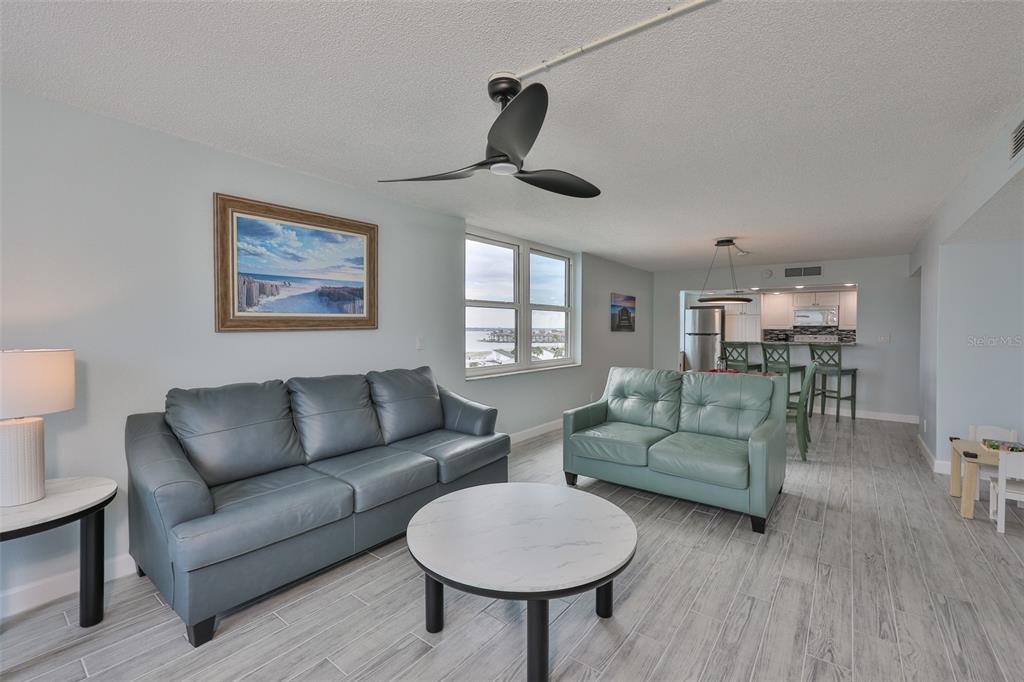 A living room with two leather sofas, a round coffee table, and an open kitchen — 1400 GULF BOULEVARD UNIT 704, CLEARWATER BEACH, FL