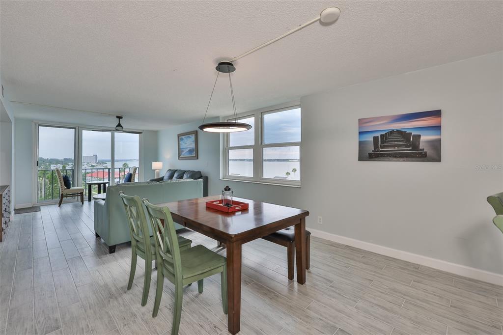 A dining area with a wooden table and green chairs overlooks a water view — 1400 GULF BOULEVARD UNIT 704, CLEARWATER BEACH, FL