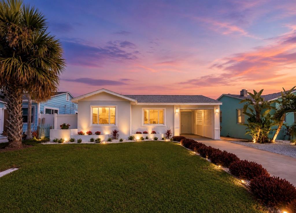 A single-story house with a white exterior, palm tree, and illuminated landscaping at sunset — 480 S BAYSHORE DRIVE, MADEIRA BEACH, FL