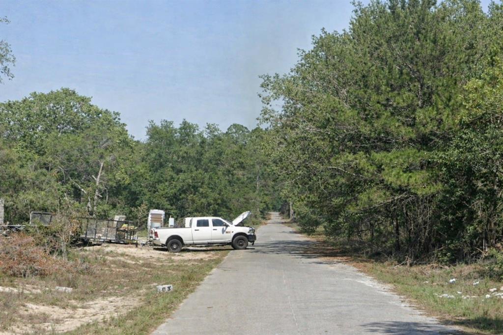 A white pickup truck with its hood open is parked on a rural paved road — MALAUKA PASS TRL, OCKLAWAHA, FL