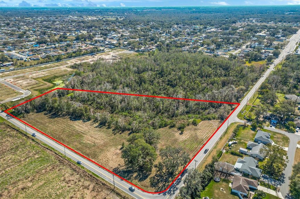 An aerial view shows a triangular, partially wooded plot of land bordered by two roads — 7835 KATHLEEN ROAD, LAKELAND, FL