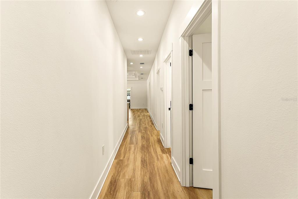 A long hallway with white walls, recessed lighting, and wood-look flooring — 2922 W GIDDENS AVENUE, TAMPA, FL