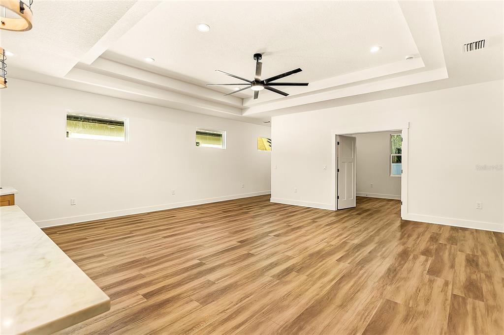 A spacious room with wood-look flooring, a tray ceiling, and a ceiling fan — 2922 W GIDDENS AVENUE, TAMPA, FL