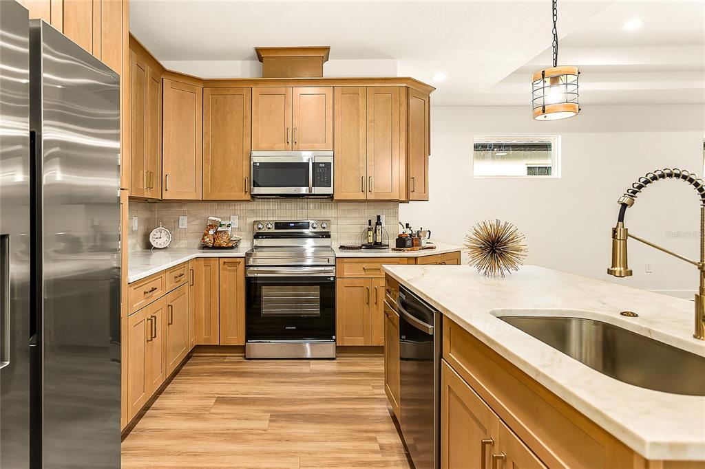 A kitchen with light wood cabinets, stainless steel appliances, and a marble-topped island with sink — 2922 W GIDDENS AVENUE, TAMPA, FL