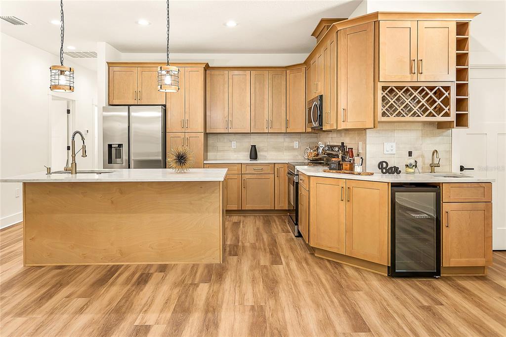 A kitchen with light wood cabinets, stainless steel appliances, a kitchen island, and wood flooring — 2922 W GIDDENS AVENUE, TAMPA, FL