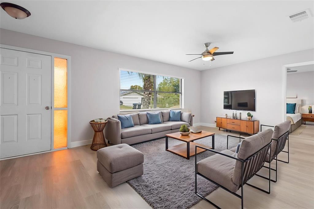 A living room features light wood floors, a gray sofa, two armchairs, and a television — 10140 BRIDLEWOOD AVENUE, ORLANDO, FL