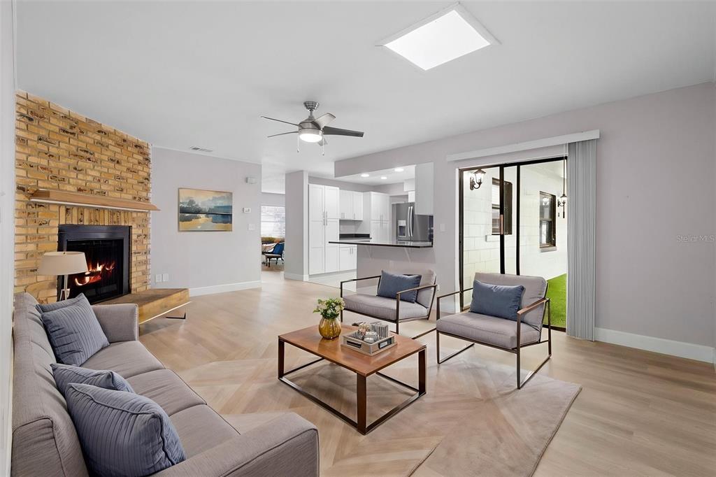 A living room features a brick fireplace, light wood flooring, and an open kitchen area — 10140 BRIDLEWOOD AVENUE, ORLANDO, FL