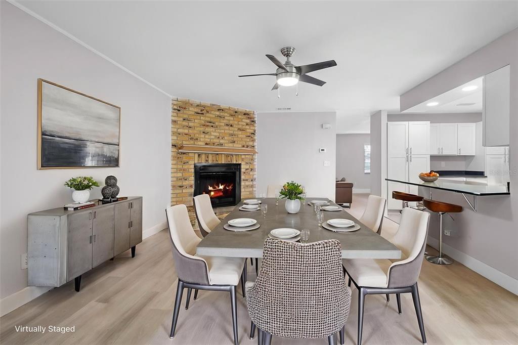 A dining room features a concrete table, a brick fireplace, and an adjacent kitchen area — 10140 BRIDLEWOOD AVENUE, ORLANDO, FL