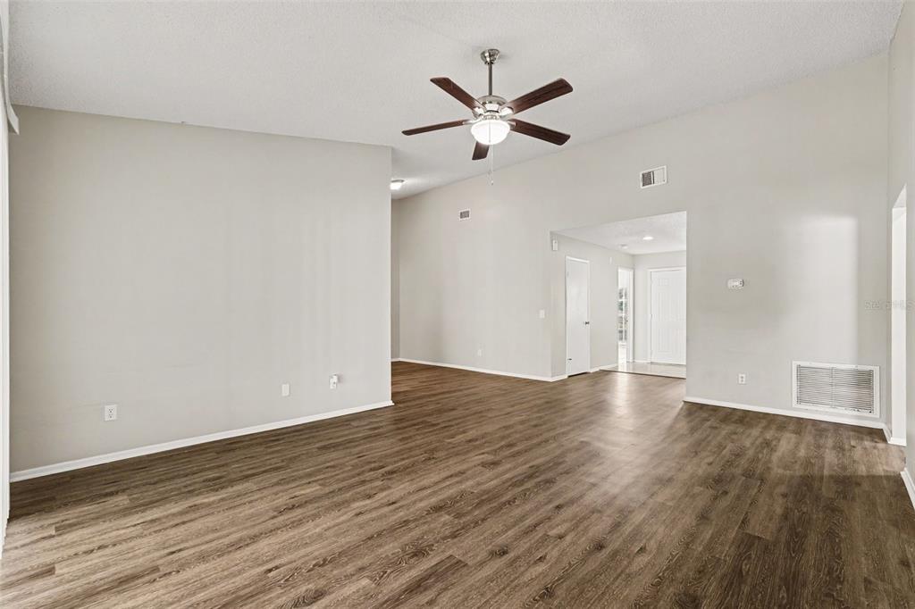 An empty living room features light gray walls, wood-look flooring, and a ceiling fan — 8304 NATCHEZ STREET, TAMPA, FL