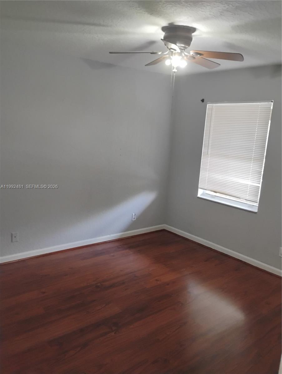 An empty bedroom features light gray walls, dark wood-look flooring, and a ceiling fan — 3748 NW 91st Ln # 3748, Sunrise FL 33351, SUNRISE, FL