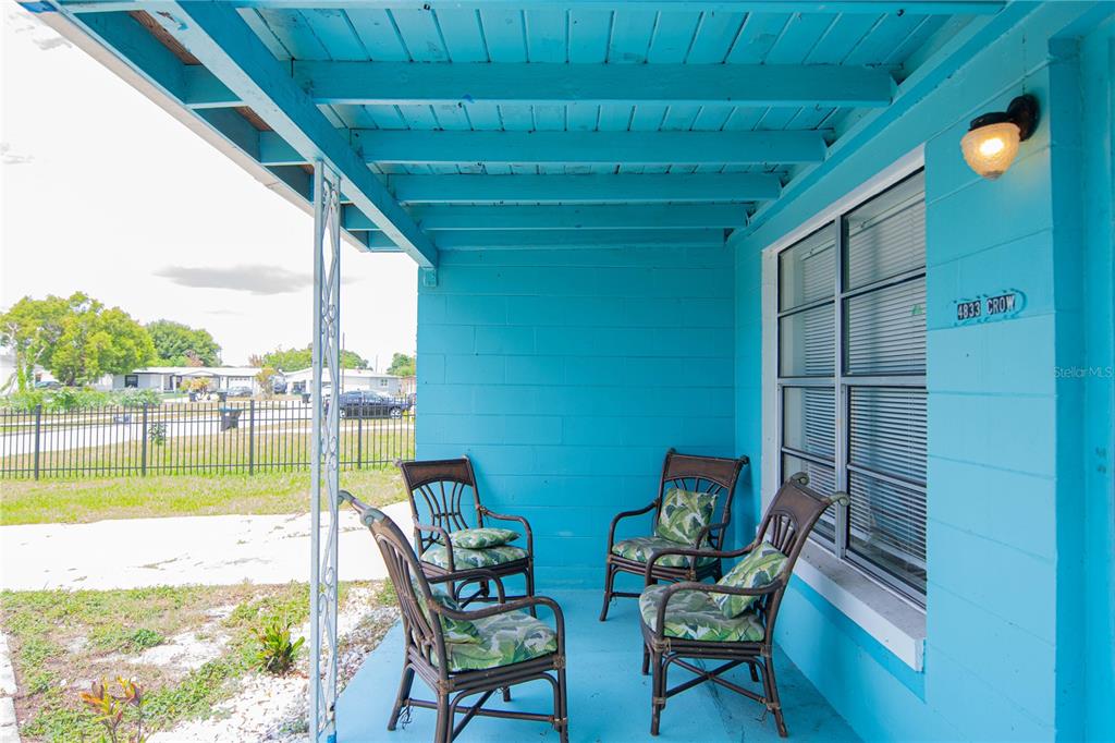 A covered front porch features bright blue walls, exposed ceiling beams, and four wicker chairs — 4833 CROW STREET, ORLANDO, FL