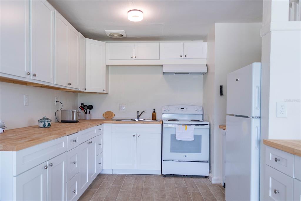 A kitchen features white cabinets, butcher block countertops, a white stove, and a refrigerator — 4833 CROW STREET, ORLANDO, FL