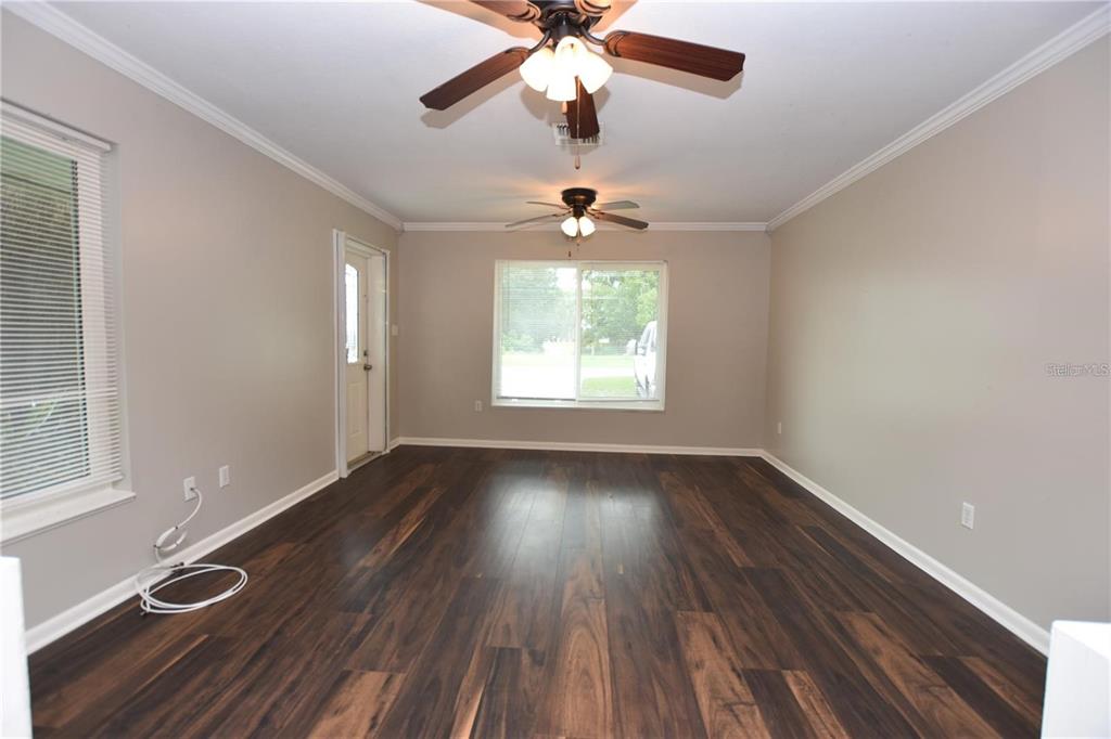 An empty room features dark wood-look flooring, light gray walls, and two ceiling fans — 928 E VALENCIA STREET, LAKELAND, FL