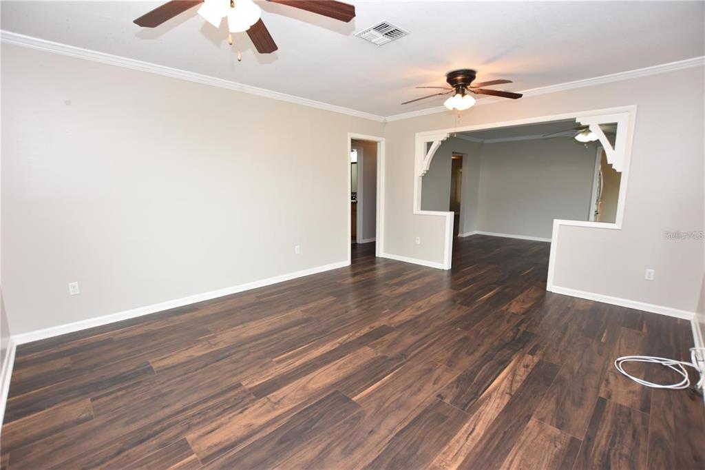 A living room with dark wood-look flooring, light walls, and two ceiling fans — 928 E VALENCIA STREET, LAKELAND, FL