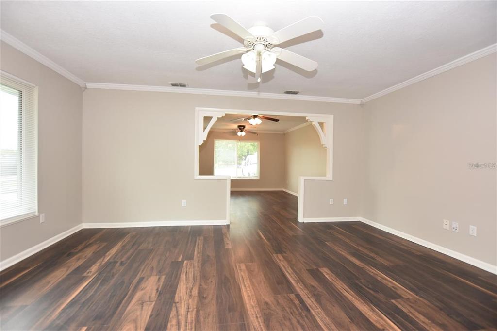 A living room with dark wood-look flooring, light gray walls, and a ceiling fan — 928 E VALENCIA STREET, LAKELAND, FL