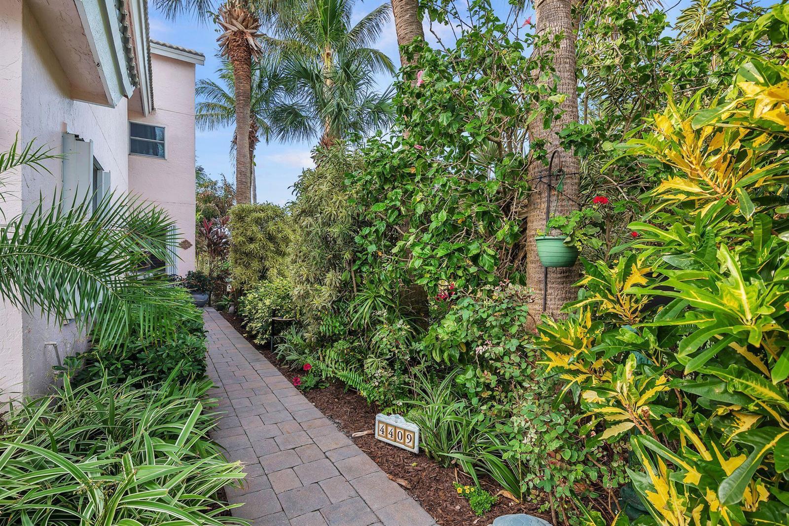 A paved walkway leads past lush tropical landscaping and a house number sign — 4409 N Fairway Dr Drive N, Jupiter FL 33477, JUPITER, FL