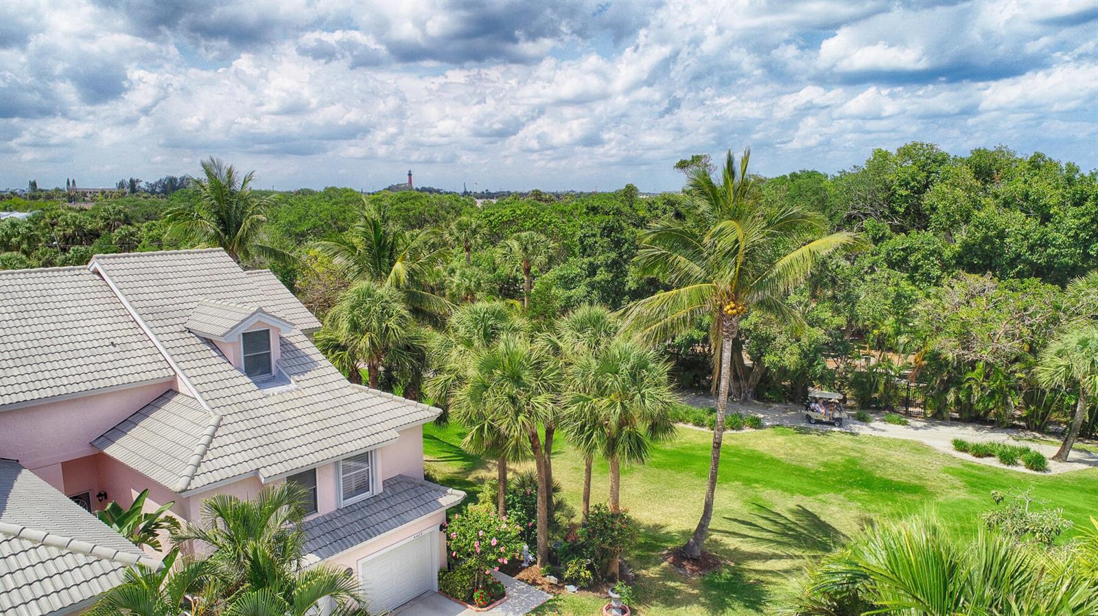An aerial view shows a pink house with a gray roof surrounded by lush trees — 4409 N Fairway Dr Drive N, Jupiter FL 33477, JUPITER, FL