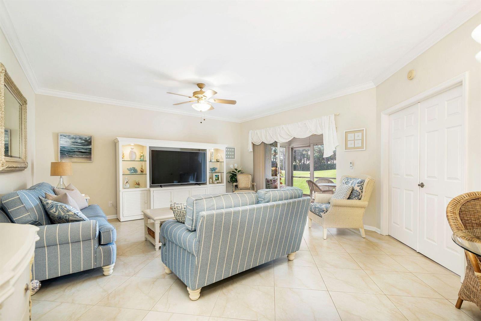 A living room features blue striped sofas, a white entertainment center, and tile flooring — 4409 N Fairway Dr Drive N, Jupiter FL 33477, JUPITER, FL