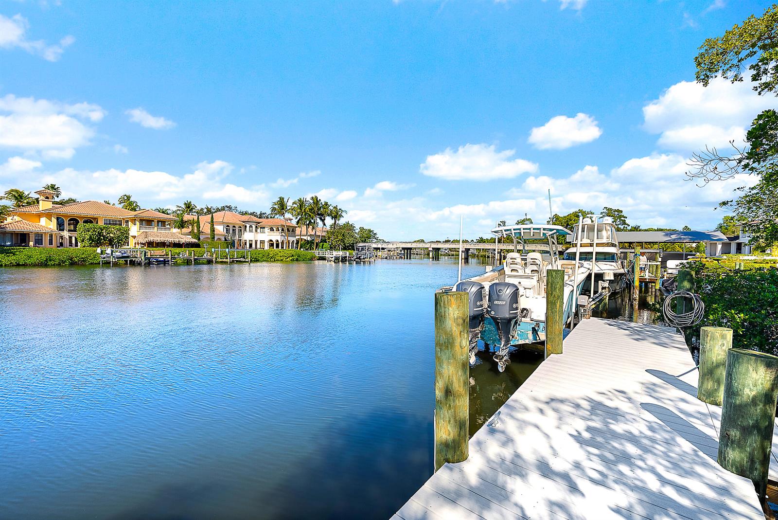 A boat is docked at a wooden pier on a canal lined with large houses — 9176 SE River Terrace, Jupiter FL 33469, JUPITER, FL