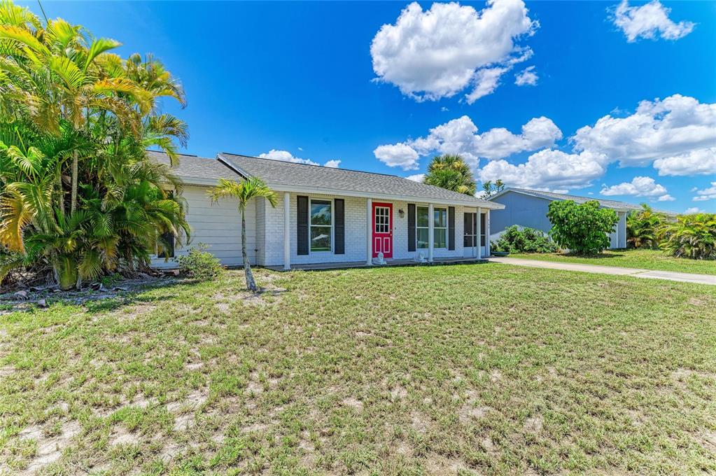 A single-story house with white siding, a red front door, and a grassy front yard — 6195 LA PORTE TERRACE, PORT CHARLOTTE, FL
