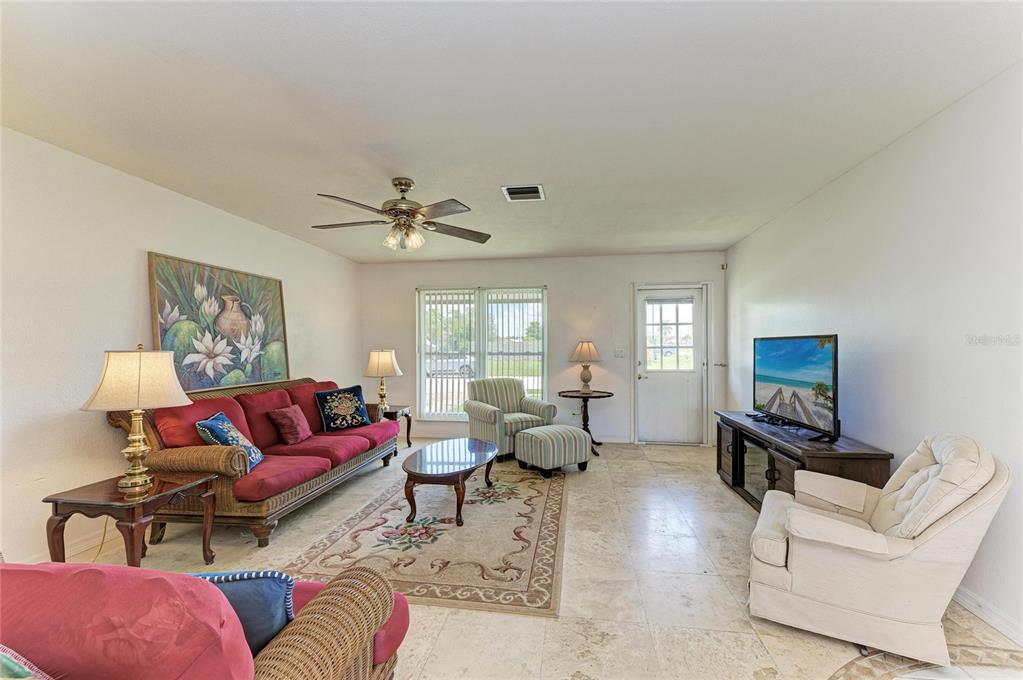 A living room features tile flooring, a red sofa, a patterned rug, and a television — 6195 LA PORTE TERRACE, PORT CHARLOTTE, FL