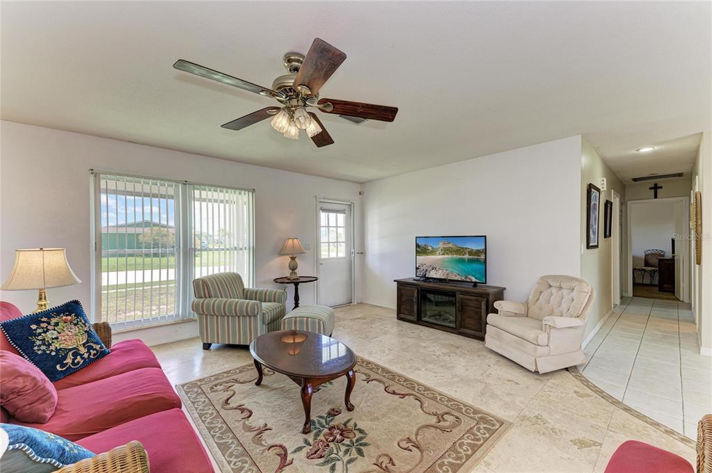 A living room features tile floors, a ceiling fan, a television console, and patio access — 6195 LA PORTE TERRACE, PORT CHARLOTTE, FL