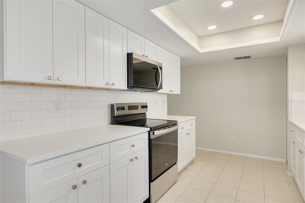 This is a digitally staged living and dining room with tile floors and mirrored walls — 3569 OAK LAKE DRIVE, PALM HARBOR, FL