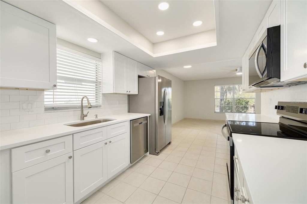 A bedroom features a bed with white bedding, a ceiling fan, and an attached bathroom — 3569 OAK LAKE DRIVE, PALM HARBOR, FL