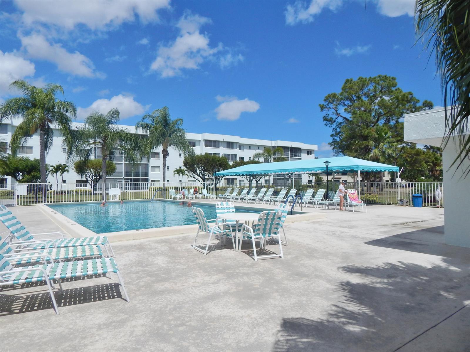 A swimming pool area features lounge chairs, a shaded patio, and palm trees outdoors — 6698 N 10th Ave N # 215, Lake Worth FL 33467, LAKE WORTH, FL