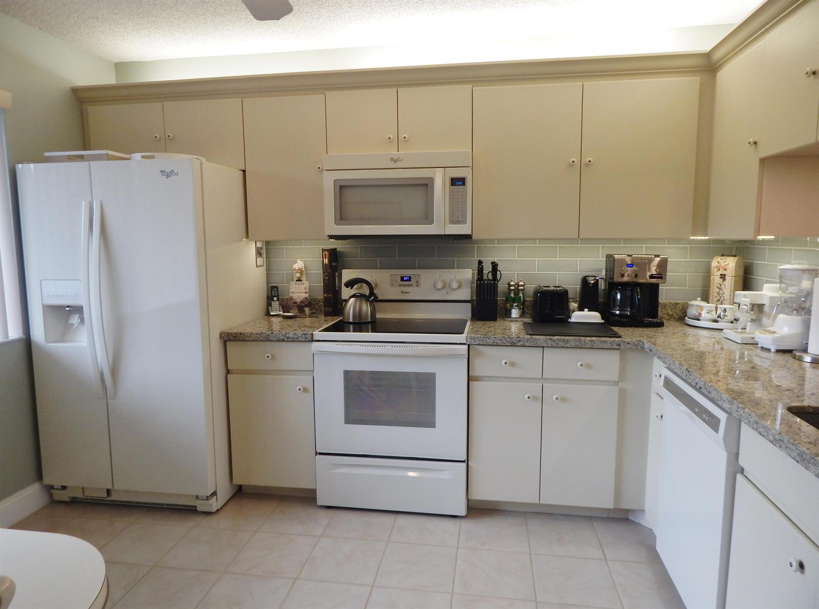 A kitchen with white appliances, light-colored cabinets, and granite countertops — 6698 N 10th Ave N # 215, Lake Worth FL 33467, LAKE WORTH, FL