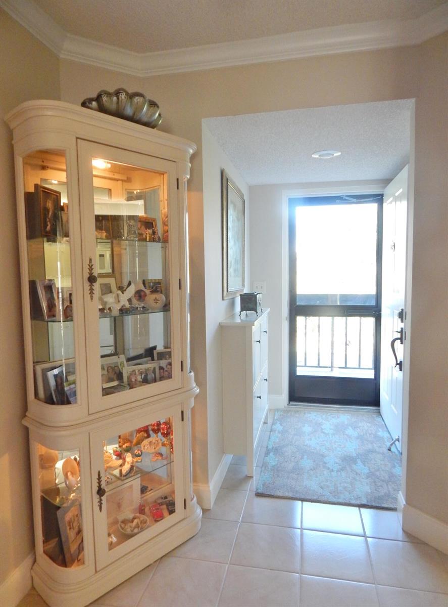 A tiled entryway features a large white curio cabinet, a slim shoe cabinet, and a door — 6698 N 10th Ave N # 215, Lake Worth FL 33467, LAKE WORTH, FL
