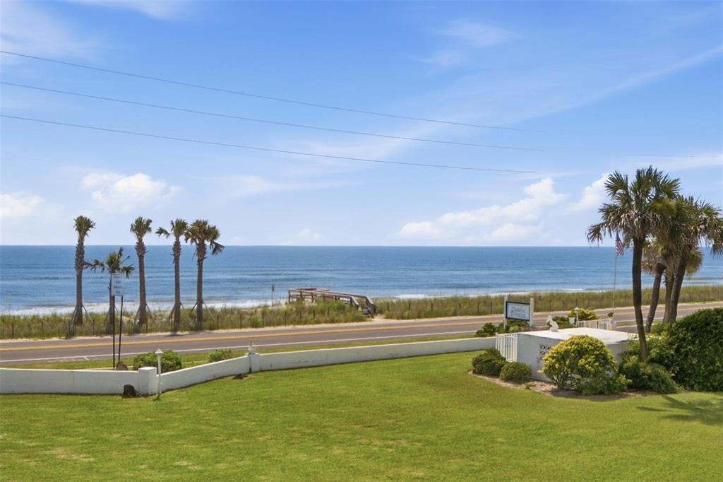A grassy lawn overlooks a road, sand dunes, and the ocean under a blue sky — 3510 S OCEAN SHORE BOULEVARD UNIT 217, FLAGLER BEACH, FL