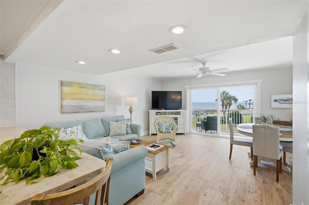 A living and dining area with light wood floors, a blue sofa, and ocean views — 3510 S OCEAN SHORE BOULEVARD UNIT 217, FLAGLER BEACH, FL